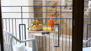 A balcony with a table set with fruits, glasses, and a hat.