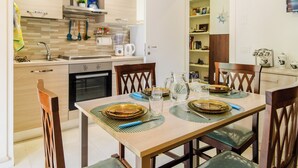A modern kitchen with a dining table set for four, equipped with a coffee maker, blender, and various utensils.