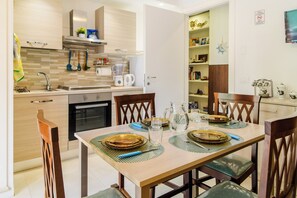 A modern kitchen with a dining table set for four, equipped with a coffee maker, blender, and various kitchen utensils. - B&B-Apartment-Sleeps3-Parking-Balcony-PetFriendly (Sorrento)