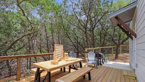 A wooden deck with a table and chairs, a wooden bench, and a game board.