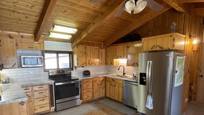 A kitchen with wooden cabinets, a stainless steel refrigerator, a microwave, and a stove.