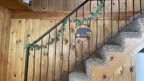 A wooden staircase with a metal railing, decorated with a garland and a bear silhouette.