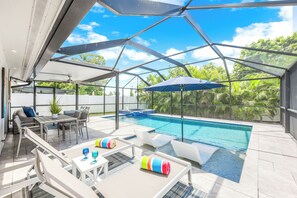 Un área de piscina exterior moderna con cerramiento de vidrio, sillas de descanso y un jacuzzi.