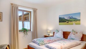 Una camera da letto con un letto in legno, una finestra con tende, un comodino con una lampada e un dipinto raffigurante un paesaggio sulla parete.
