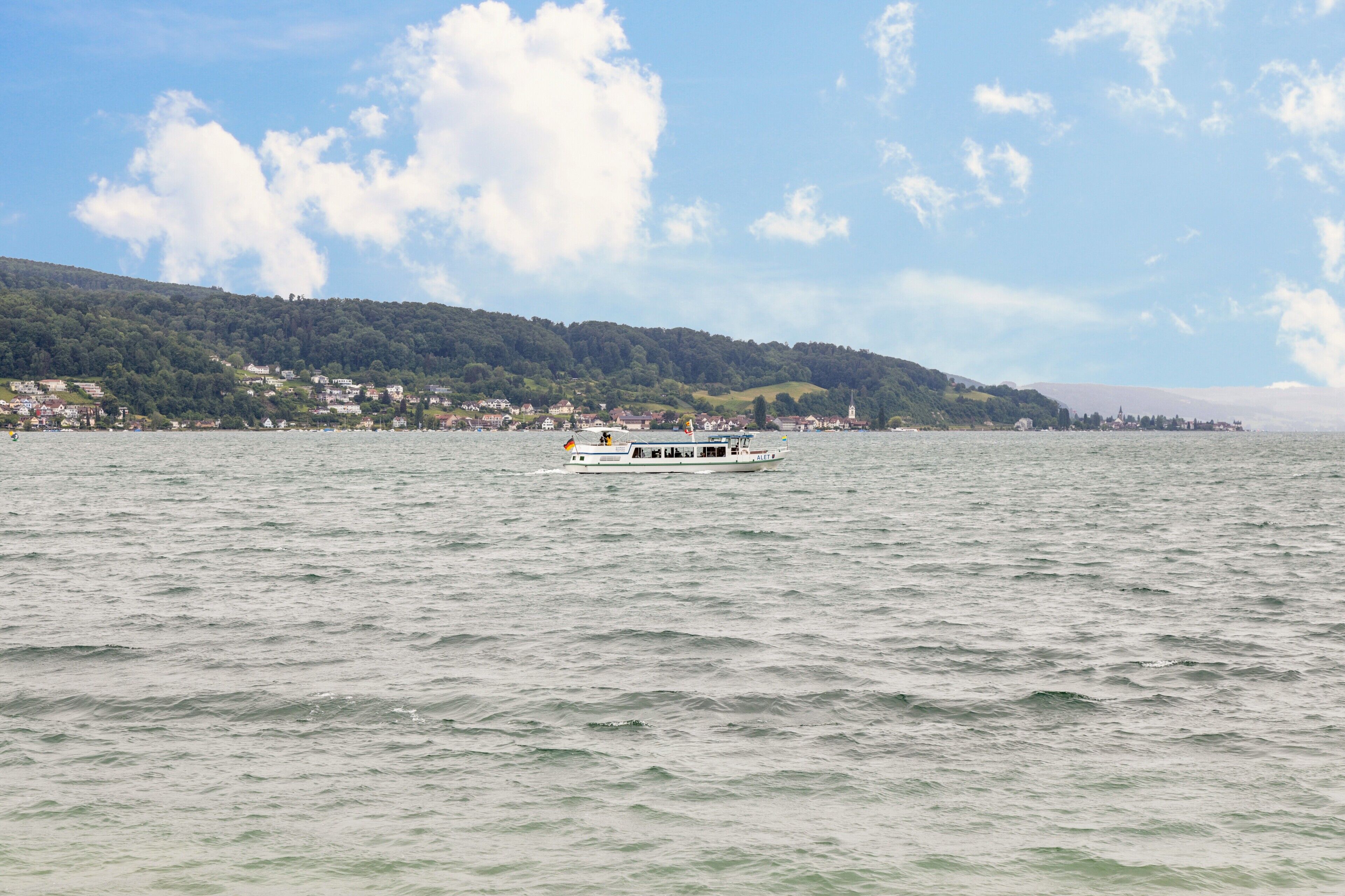 Ein Boot auf einem ruhigen See mit einer Stadt im Hintergrund.