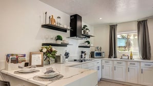 A modern kitchen with white cabinets, a marble island, a microwave, and a window with curtains. - New! Majestic VIEWS, HIKING, Modern Guest Suite (Sedona)