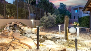 A landscaped garden with a rock formation, a small waterfall, and a modern building in the background. - New! Majestic VIEWS, HIKING, Modern Guest Suite (Sedona)
