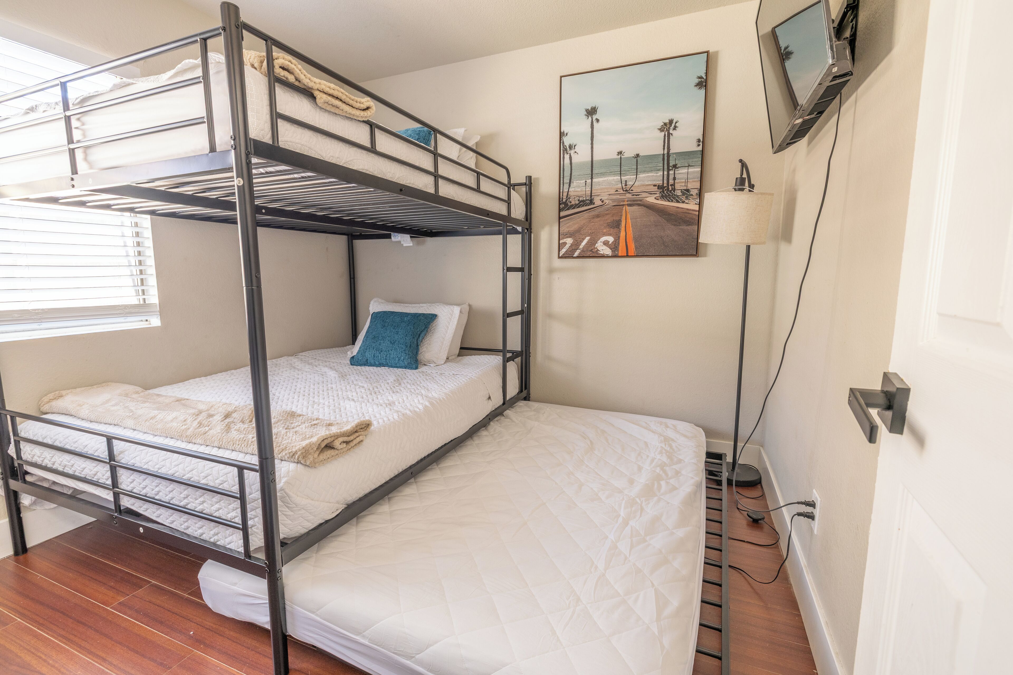 Habitación con literas, un cuadro con temática marina, una lámpara de escritorio y un televisor montado en la pared.