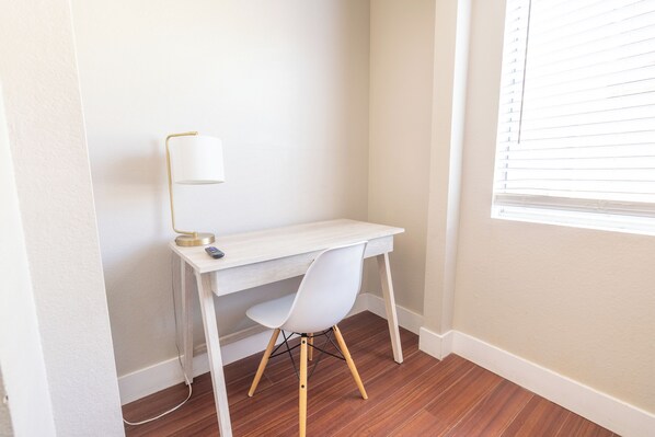 A corner office with a white desk, a white chair, and a floor lamp.