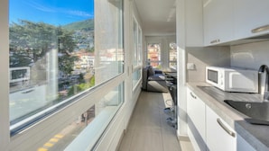 A narrow balcony with a city view, a kitchen with a microwave, and a seating area with a sofa. - Casa Cupido Locarno Walk to Lake & Centre, Locarno, Switzerland (Locarno)