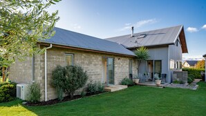 A modern house with a stone facade, a sloped metal roof, and a well-maintained lawn. - Mountain View Bliss - Albert Town Holiday Unit (Albert Town)