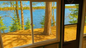 Eine Hütte mit einem großen Fenster mit Blick auf einen See, der von Bäumen umgeben ist.