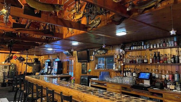 Un bar au décor en bois, avec des poissons décoratifs fixés au plafond et des étagères remplies de bouteilles.