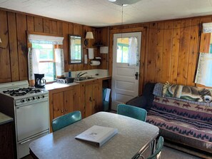 Ein Ferienhaus-Innenraum mit Küchenbereich, einem Esstisch und einer Couch mit Decke.