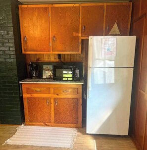 Cocina pequeña con armarios de madera, microondas y refrigerador.