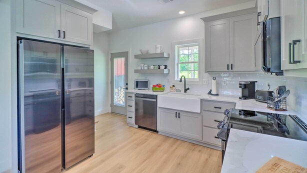 Una cocina moderna con electrodomésticos de acero inoxidable, armarios blancos y una isla grande con horno integrado.