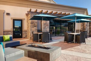 Un espacio patio al aire libre con paredes de piedra, mobiliario de mimbre y una chimenea.