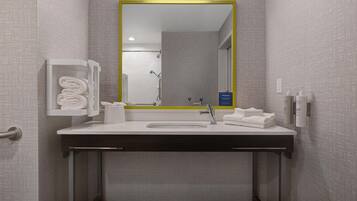 Une salle de bain moderne avec un lavabo blanc, un miroir doté d’un cadre jaune et un porte-serviettes.