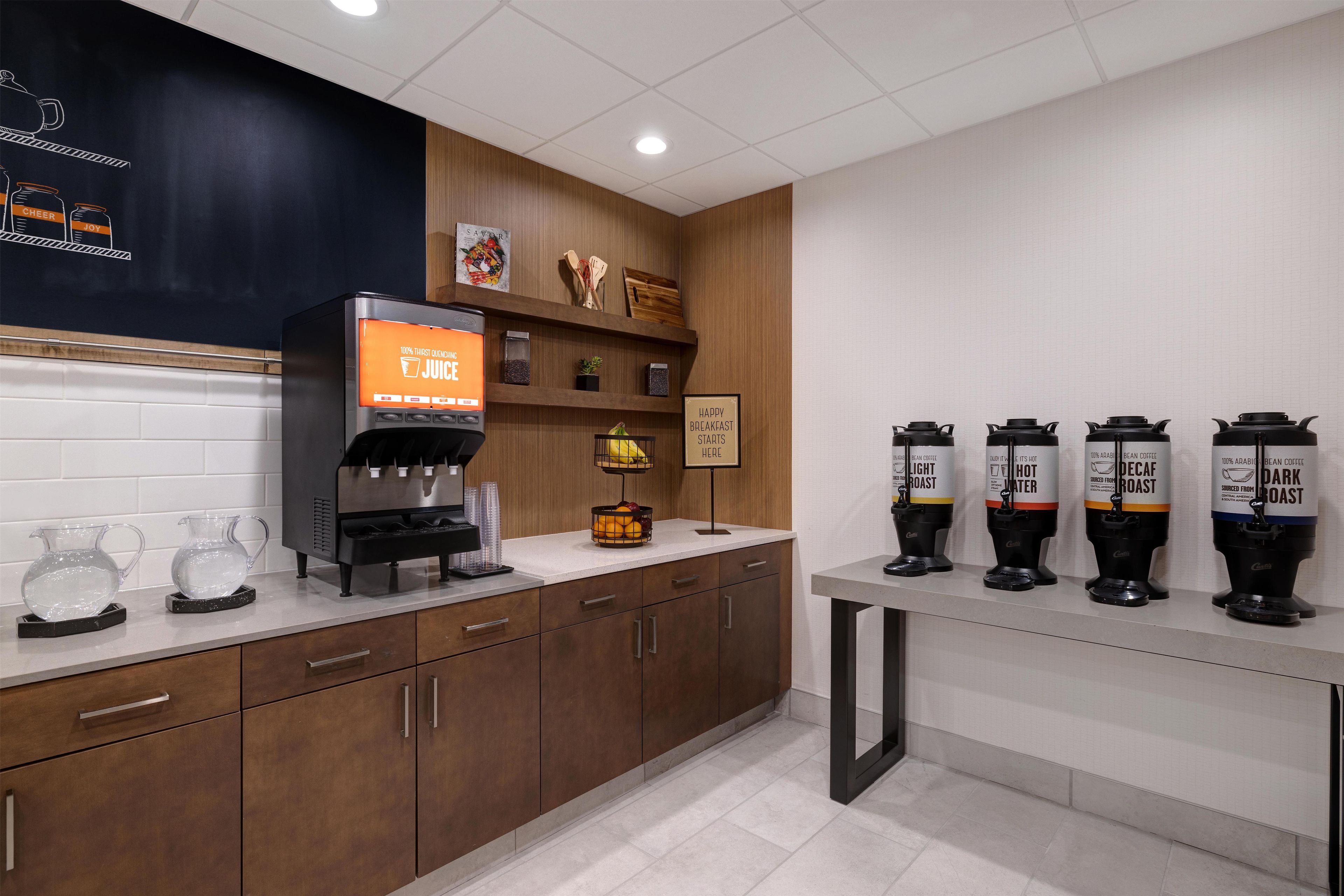 A kitchen area with a coffee machine, a fruit bowl, and multiple coffee dispensers.