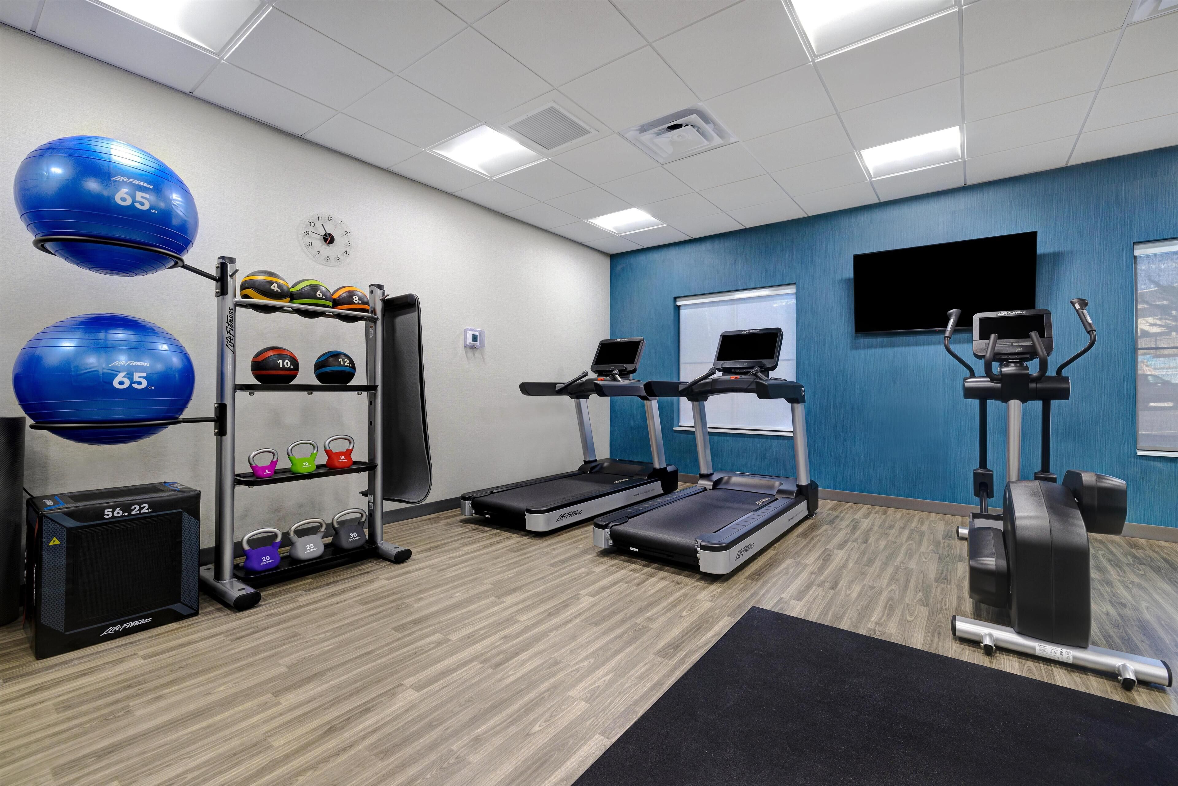 Ett gym med löpband, träningsbollar och viktskivor.