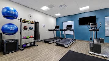Ett gym med löpband, träningsbollar och viktskivor.