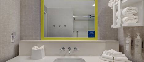 Et badeværelse med vask, spejl, håndklædestativ og toiletartikler.