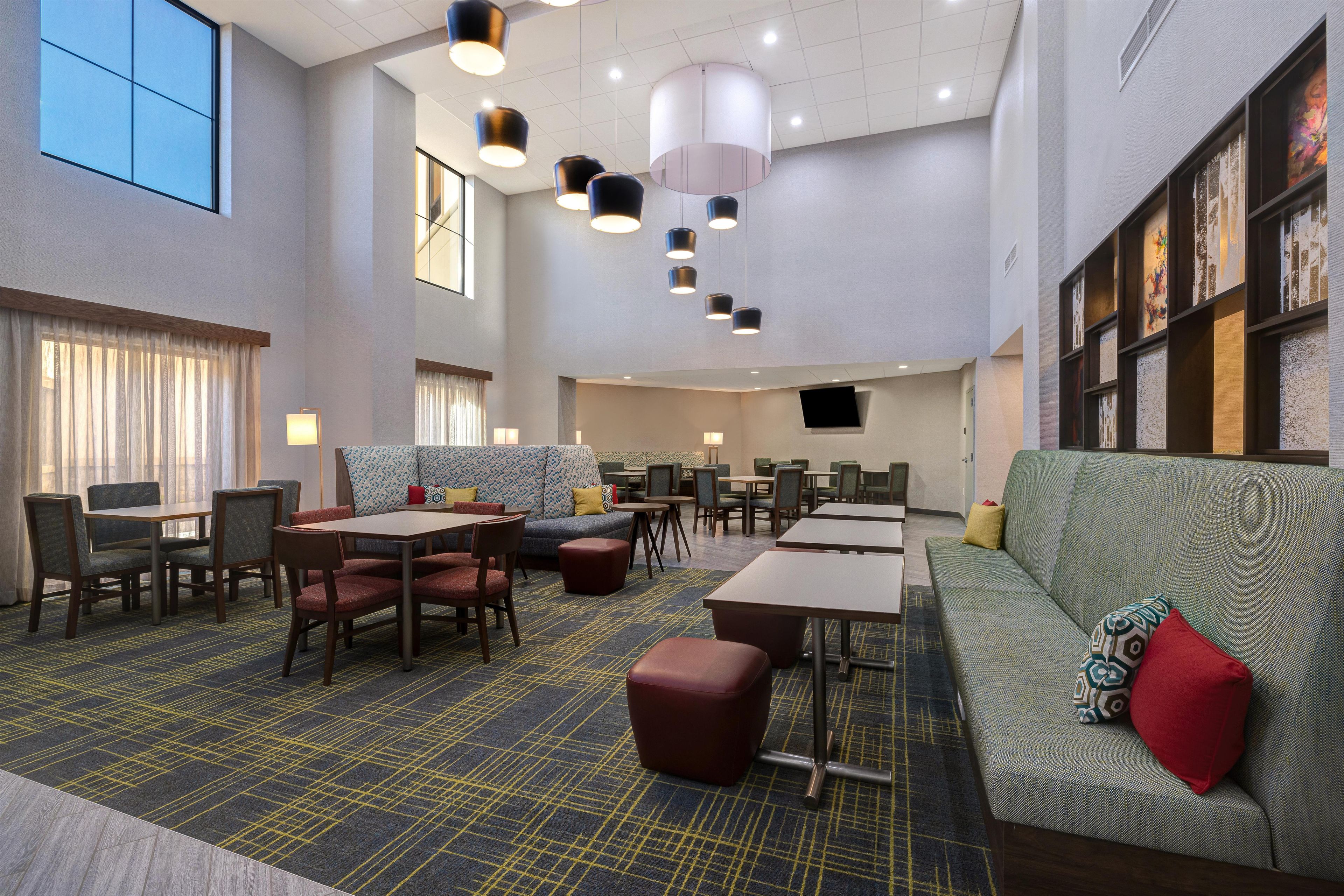 A hotel lobby with a seating area, tables, and a large window.