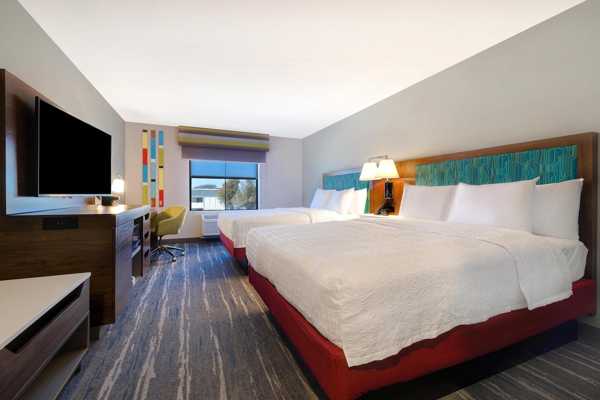 Een hotelkamer met een groot bed, een bureau, een televisie en een raam met uitzicht.