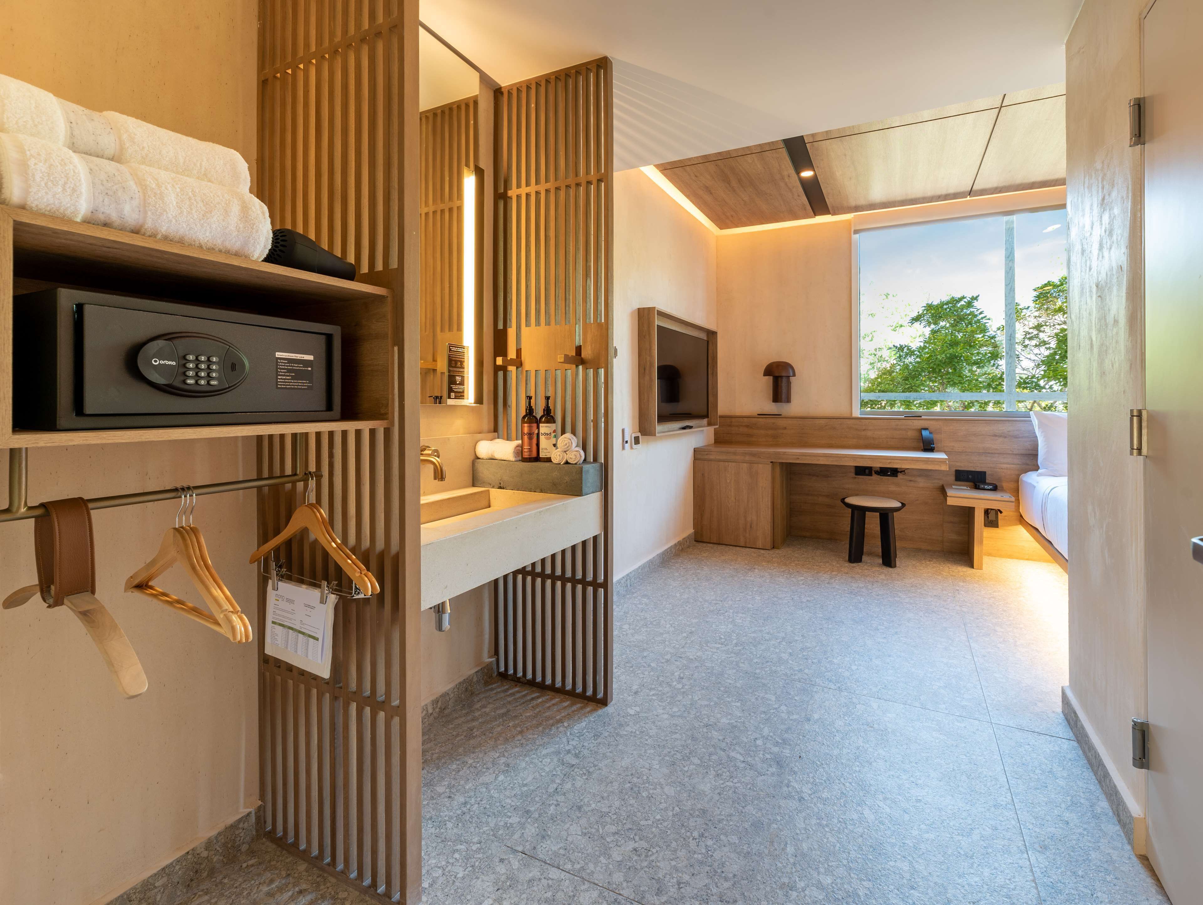 Habitación de hotel moderna con escritorio integrado, ventana grande con vistas, zona de ducha y minibar.