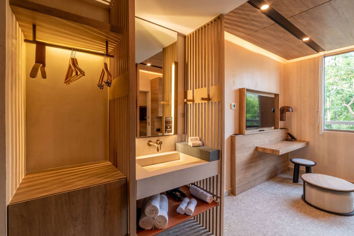 A modern bathroom with wooden paneling, a large mirror, a sink, and a toilet.