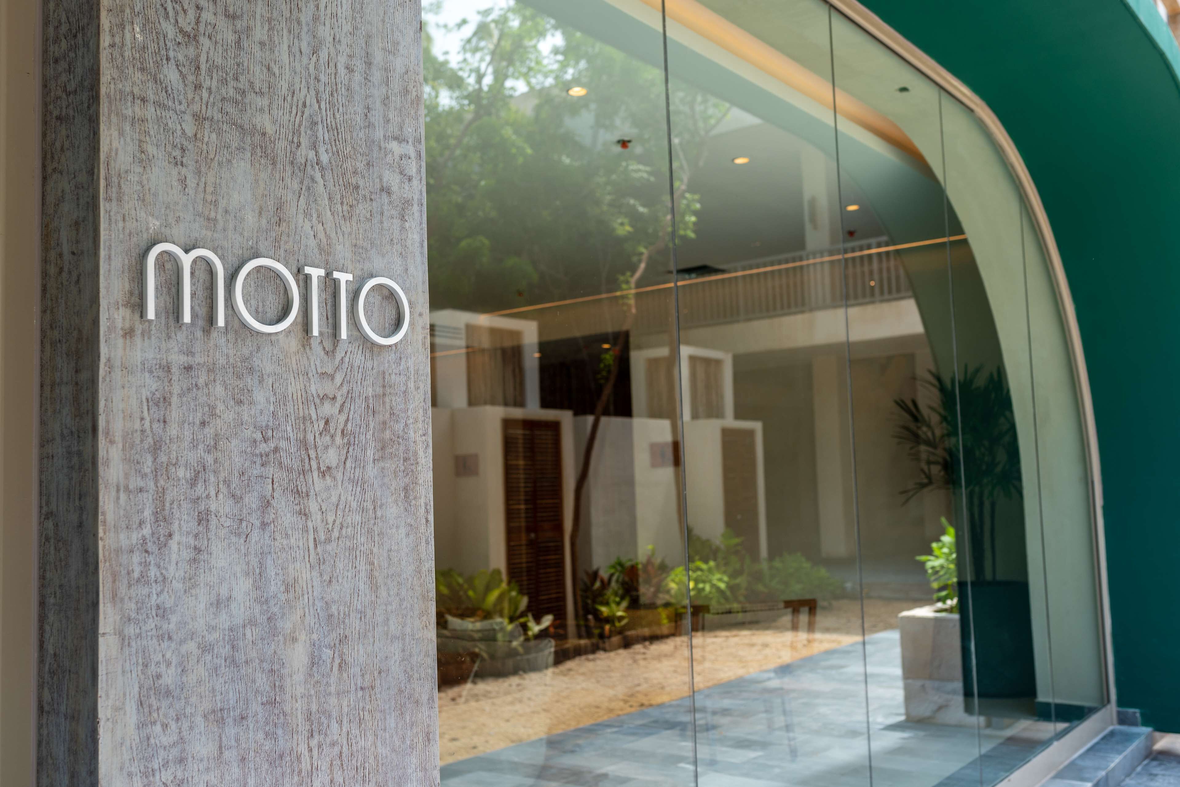A modern building entrance with a glass facade and the name "Motto" displayed prominently.