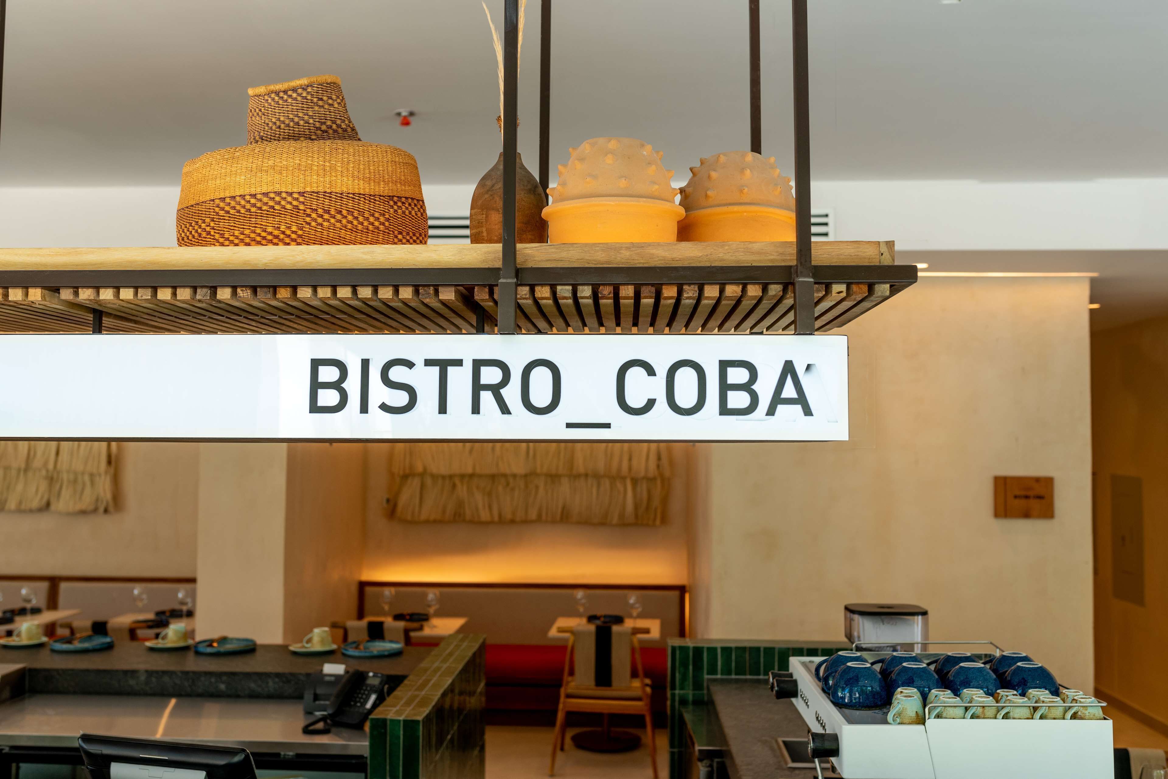 A bistro with a sign reading 'BISTRO COBA' hanging above a counter with various items.