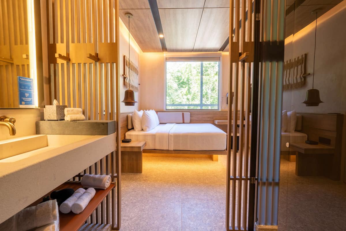 A modern bedroom with a large window, a wooden ceiling, and a built-in bench.