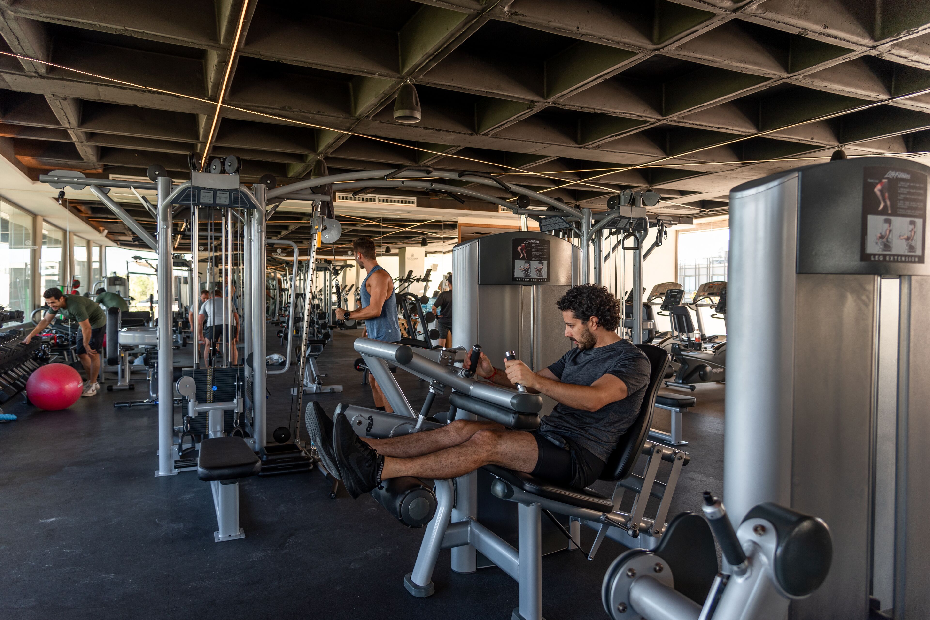 A gym with various exercise machines and a ceiling with exposed beams.