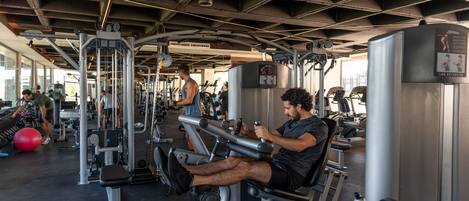 A gym with various exercise machines and a ceiling with exposed beams.