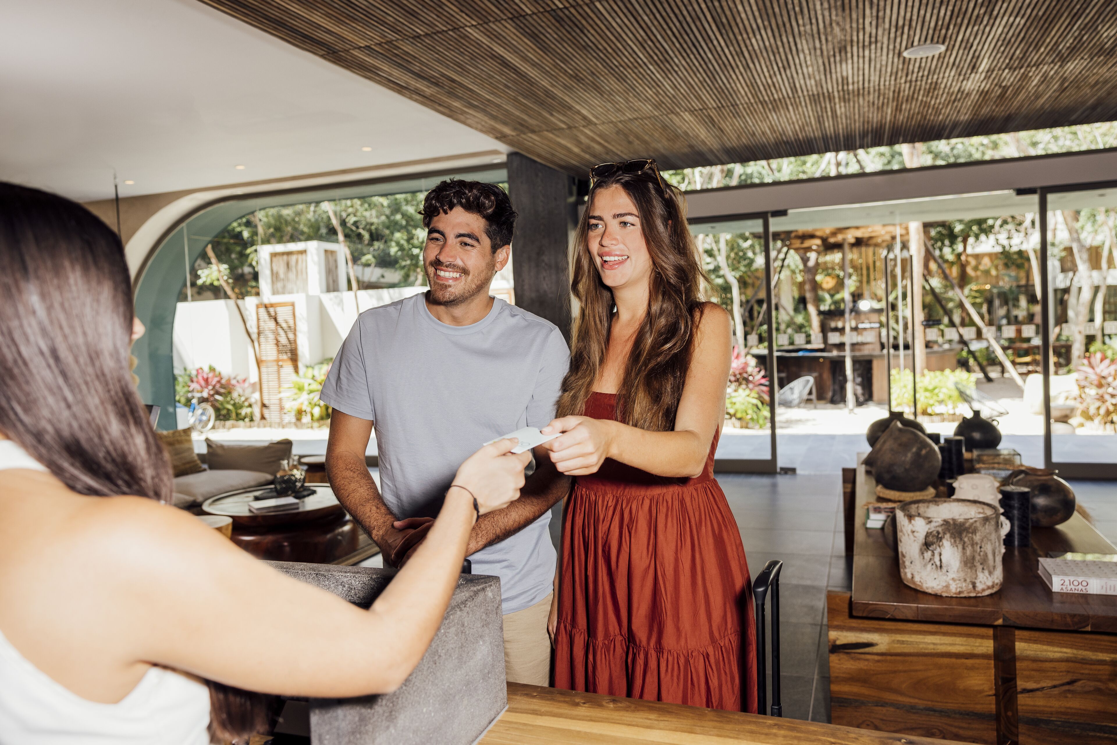 Un interior moderno con techo de madera, una zona de comedor con mesa y sillas, y vistas al exterior a través de amplios ventanales.