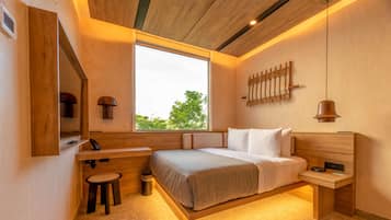 A modern bedroom with a large window, wooden headboard, bedside tables, and a small stool.