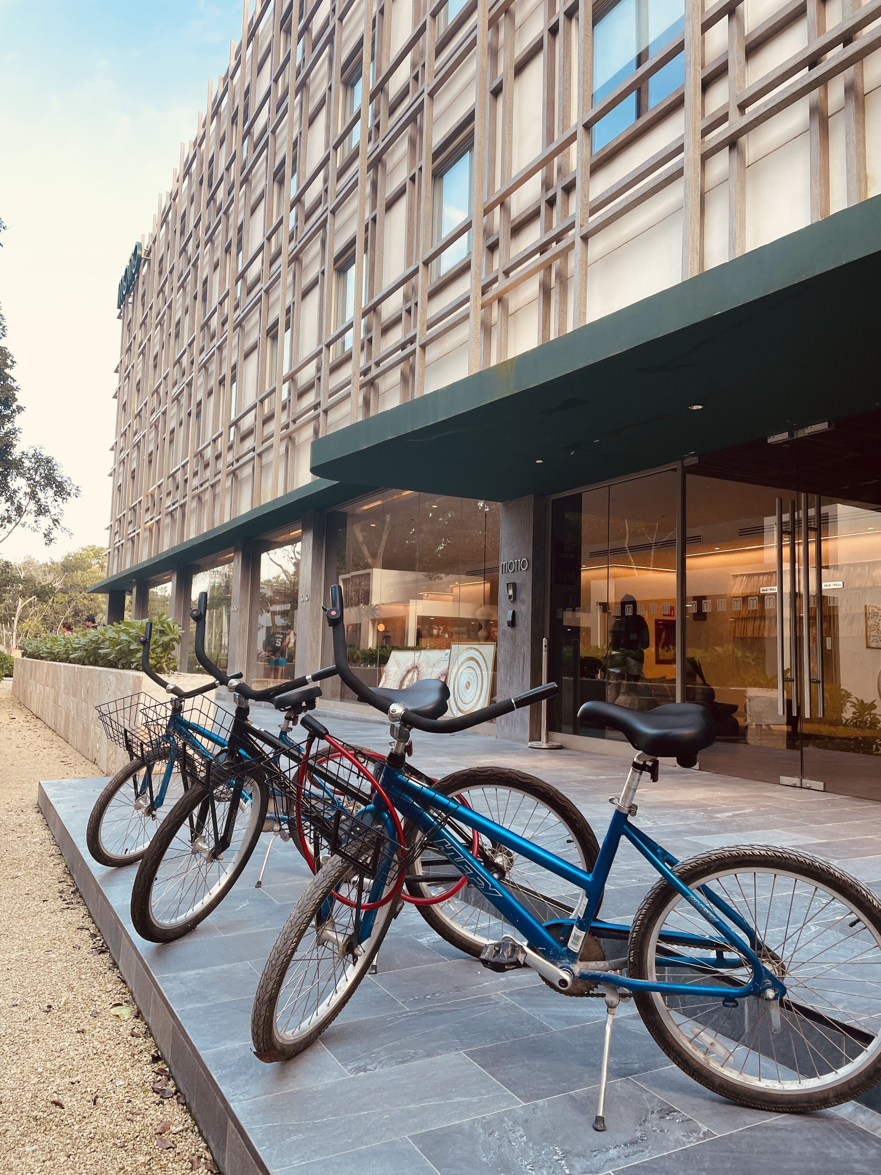A modern building with a glass facade and a bike parking area with three bicycles.