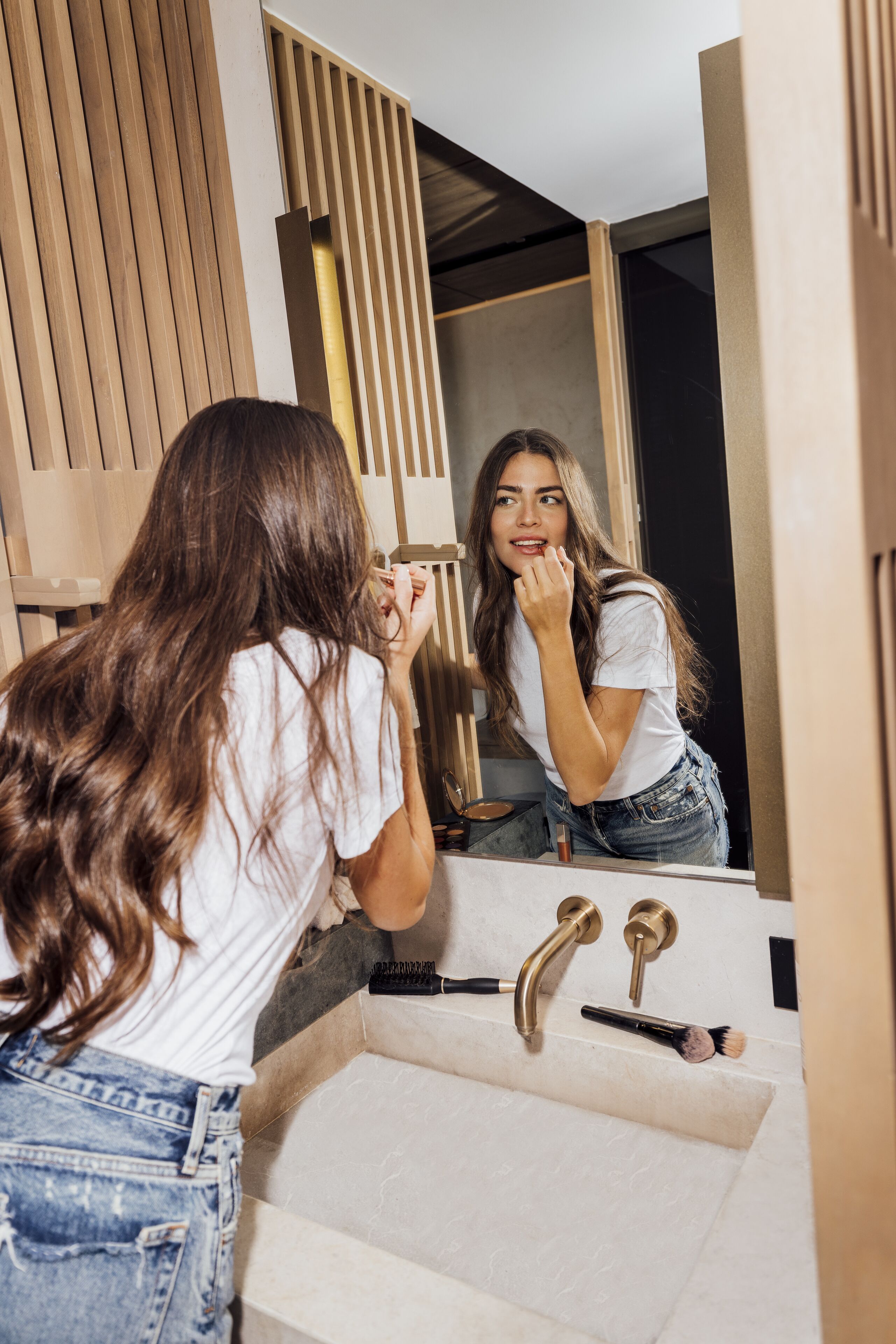 A bathroom with a sink, mirror, and wooden paneling.