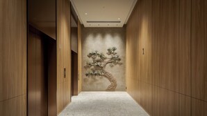 A narrow hallway with wooden paneling and a tiled floor, leading to a room with a large, textured wall mural.