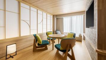 Una habitación de hotel con piso de madera, una mesa redonda y varias sillas con cojines.