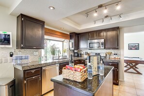 A modern kitchen with dark wood cabinets, granite countertops, and stainless steel appliances. - Home w/ Private Pool & Game Room in Indio! (Indio)