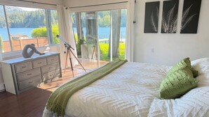 A bedroom with a large bed, a dresser, and a tripod with a camera. - West House! A beautiful lake front home with hot tub and dock. (Shawnigan Lake)