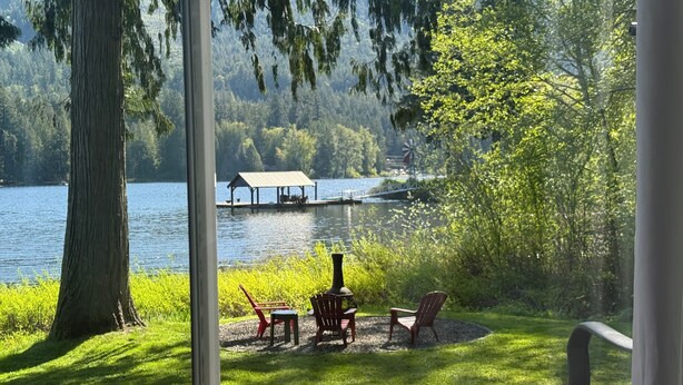 A lakeside deck with outdoor seating and a dock in the background. - West House! A beautiful lake front home with hot tub and dock. (Shawnigan Lake)