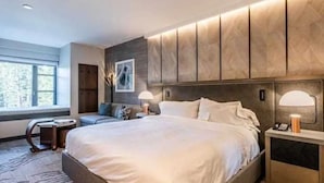 Une chambre à coucher moderne avec un grand lit, des lampes de chevet, une table de chevet et une fenêtre donnant sur des arbres.