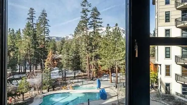 Une piscine entourée d’arbres, avec un bâtiment en arrière-plan.