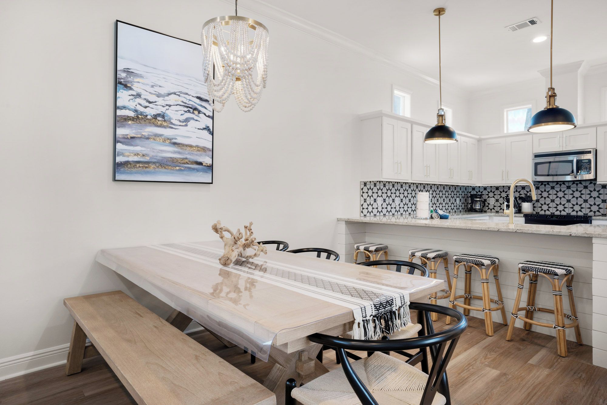 A modern kitchen with white cabinets, a black and white patterned backsplash, and a dining area with a wooden table and chairs.