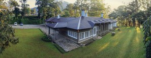 Une maison en pierre avec un toit en tuiles, de grandes fenêtres et une pelouse bien entretenue.