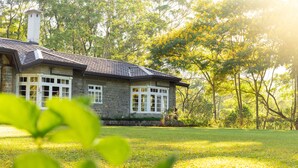 A stone house with a chimney, large windows, and a lawn in front. - The Lavender House by Reveal (Pussellawa)