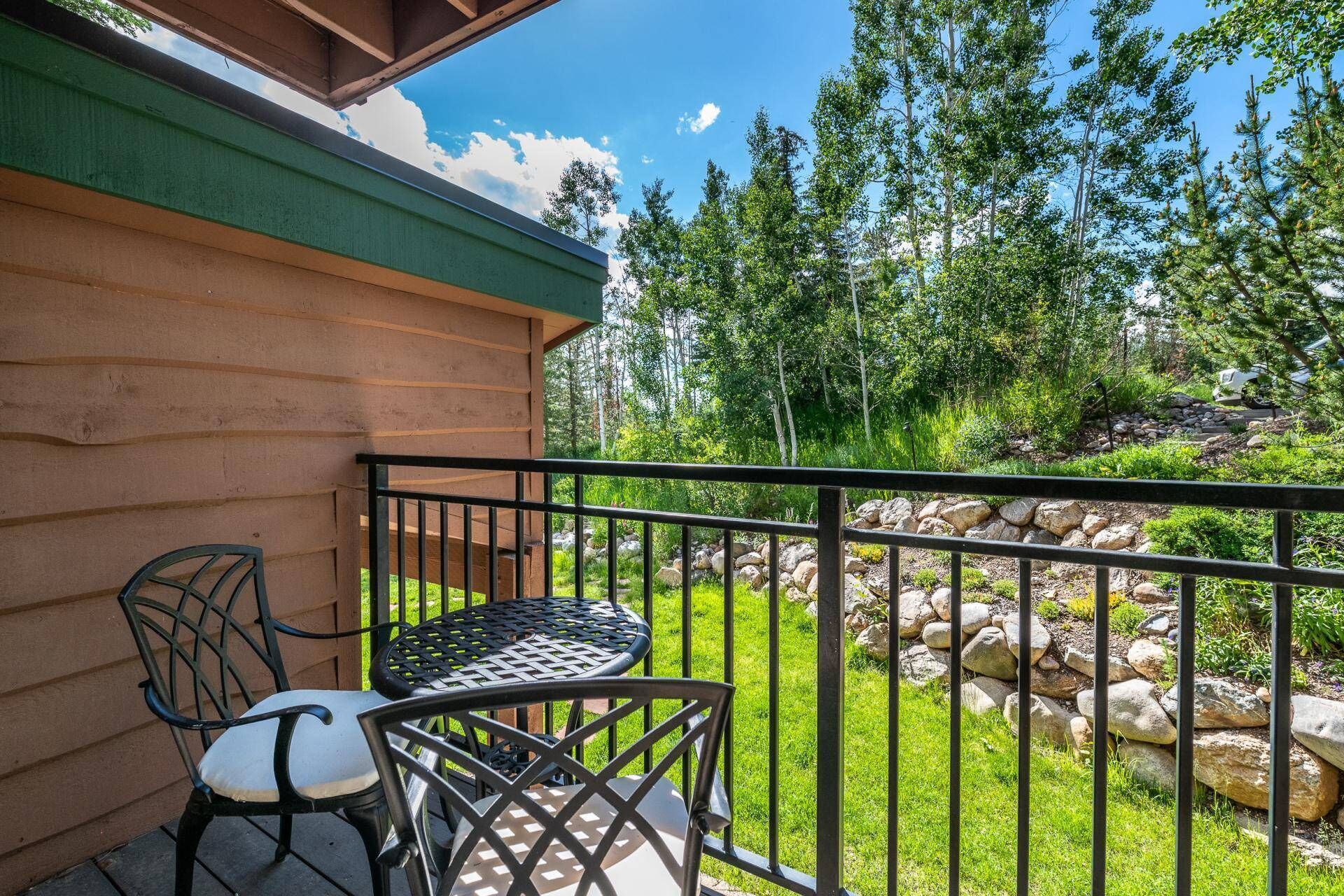 A balcony with a metal railing, two chairs, and a table.